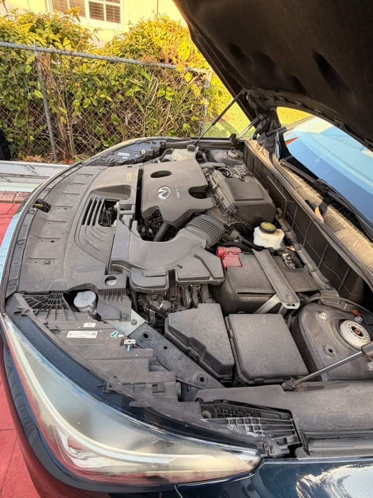 Infiniti engine compartment from the side, dusty before cleaning