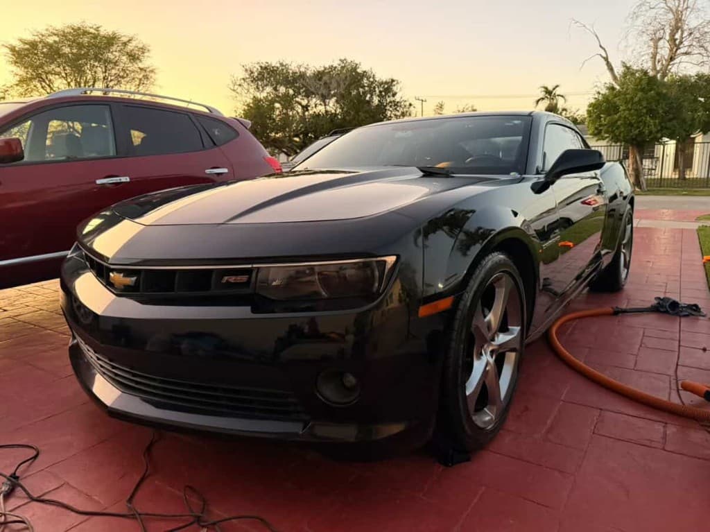 Black Chevrolet Camaro RS low front three-quarter view at sunset on a driveway