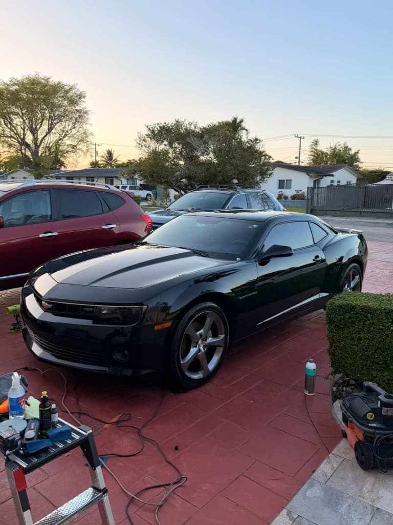 Black Chevrolet Camaro RS on driveway with detailing ladder and products